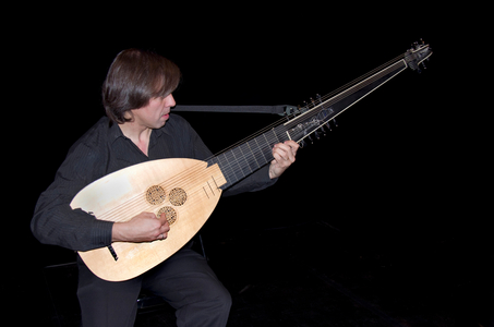 Musician playing a theorbo,a long-necked lute with a second pegbox.