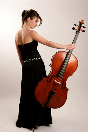 Cello -  young woman in concert dress holding  instrument. Cellist.