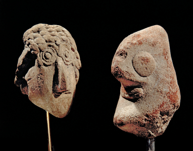Man's head, schematic, cone-shaped with big eyes and nose and probably a beard