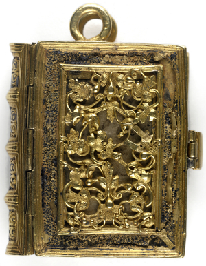 Decorated upper cover of gold open leaf tracery, with remains of black enamel in the frames round the tracery; with the two rings at the top of the covers intended for a chain tto attach the volume to the girdle. The minute volume was said to have been given by Anne Boleyn, when on the scaffold, to one of her maids of honour, a lady of the Wyat family.