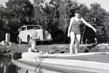 Young couple preparing for paddling in a boat on a lake, Germany 1930s (b/w photo)