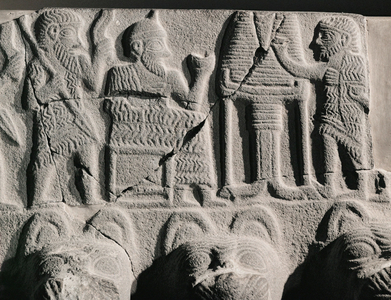 King or ruler in his role of priest seated before an offering table consecrates bread