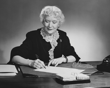 Businesswoman writing on documents with a pen in an office
