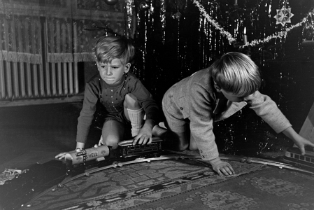 Two boys playing with the new model train under the christmas tree, Germany 1930s (b/w photo)