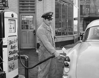 Side profile of a gas station attendant filling up a car