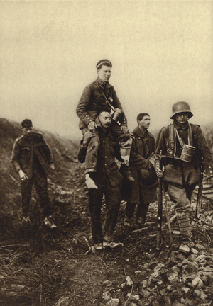 German infantryman with a leg wound being carried from the battlefield by British prisoners, World War I, 1914-1918 (b/w photo)