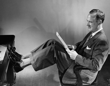 Businessman reading a paper with his legs resting on a desk