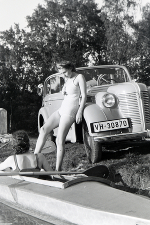 Young woman getting inside a boat, Klepper T6 with the help of a friend on a lake, Germany 1930s (b/w photo)