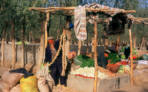 China: A Uighur man unwraps strings of garlic at an animal market and bazaar in Shufu County, near Kashgar, Xinjiang Province