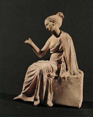 Woman with elaborate dress and headgear sitting …