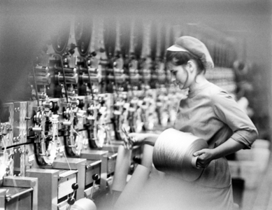 Worker removes the finished yarn spool in the VEB-Chemiefaserkombinat Guben ..., 1975 (photo)