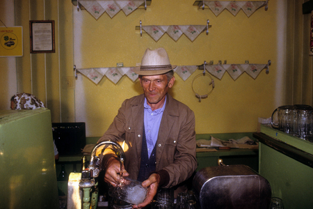 Landlord rinsing a beer glass in a village pub near Timisoara company ..., 1990 (photo)
