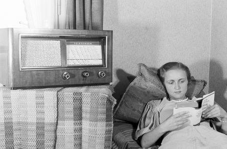 A woman lying on a sofa while listening to the radio, Germany 1930s (b/w photo)