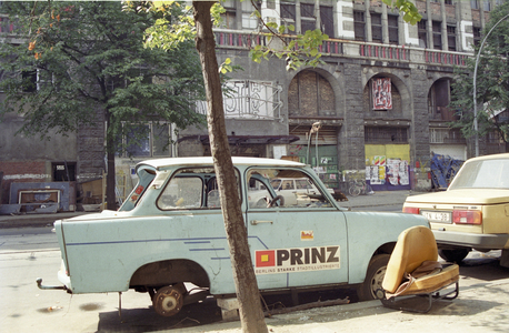 'Tacheles', in Berlin 08/91 thg Das Kunsthaus Tacheles in der Oranienburger Straße in Berlin im August 1991 Deutschland Ostberlin Ost Stadt Hauptstadt DDR Gebäude Architektur Außenansicht Kunst Künstler Künstlerinitiative besetzt besetztes Haus Kunsthaus Ruine Abbruchhaus Denkmal Denkmalschutz denkmalgeschützt geschützt vorne Vorderseite Straßenseite Trabant Trabi Trabbi Prinz Stadtmagazin Stadtillustrierte Werbung Reklame PKW Auto german architecture quer draußen (photo)