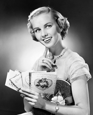 Young woman holding Valentine cards and smiling (b/w photo)