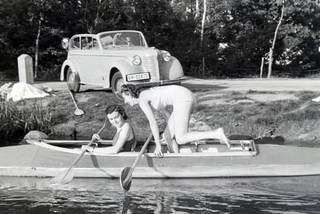 Two young woman are getting inside a boat, Klepper T6 on a lake, Germany 1930s (b/w photo)