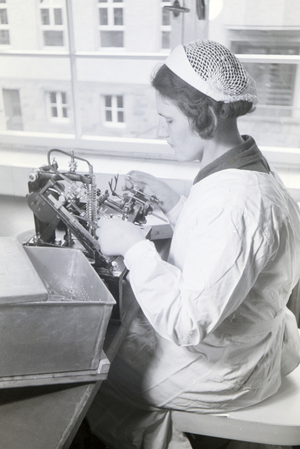 A lab assistant is taking medication samples with the help of a technical instrument in the laboratory of the Behringwerke, Marburg, Germany 1930s (b/w photo)