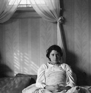 Sydelle Feinstein reclines in bed against a wall while sunlight, 1940s (photo)