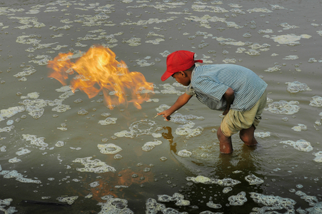 A young boy lights natural gas at the abandoned gas field in Haripur (photo)
