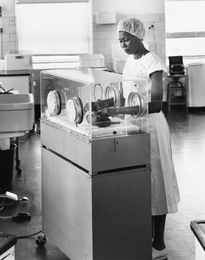 Female nurse examining a newborn baby in an incubator