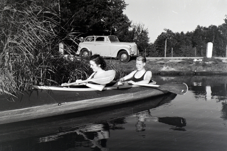 Young couple paddling in a boat on a lake near the river, Germany 1930s (b/w photo)