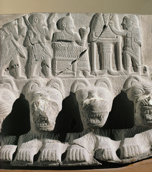 King or ruler in his role of priest seated before an offering table consecrates bread
