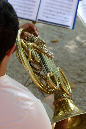 French horn and score on a music stand. Outdoors, festival time.