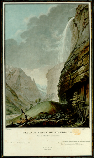 A group of figures holding parasols walk up a hill towards the rainbow forming at the bottom of Staubbach falls, with a canyon and mountains in the background