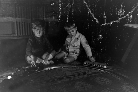 Two boys playing with the new model train under the christmas tree, Germany 1930s (b/w photo)