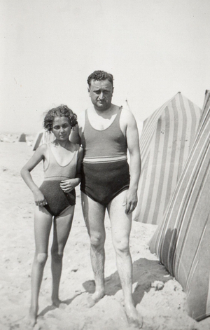 Father and daughter in swimming costumes on the beach, circa 1945 (photo)