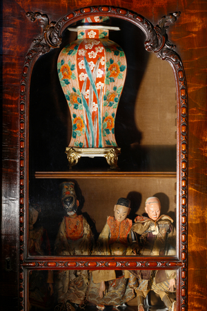 Chinese or Japanese dolls and a jar as seen in glazed window of a George III breakfro…, 2021 (photo)