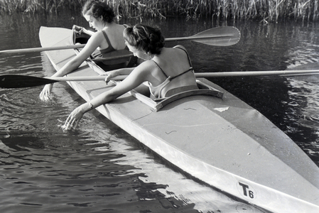 Two young women in bathing suits are paddling in a boat, Klepper T6 on a lake, Germany 1930s (b/w photo)
