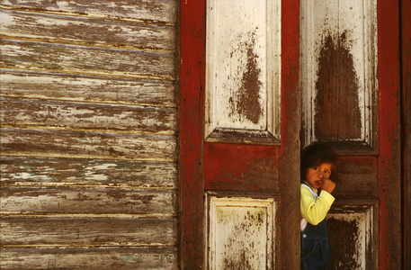 Chile,  Puerto Montt.  Girl Standing In  Weathered Doorway