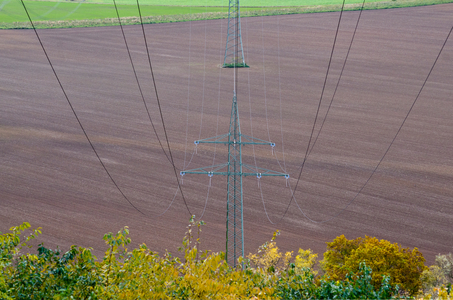 Pylon and high-voltage electricity lines sweeping across bare rural field, 2021 (photo)