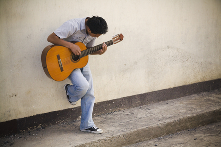Man leaning against a Wall Playing Guitar, Patzicia, Guatemala (photo)