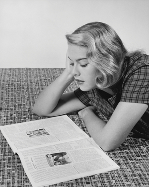 Young woman lying on the floor and reading a magazine