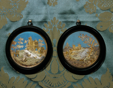 A pair of Italian capriccios, round, ebony-framed plaques showing imaginary landscapes (gilded pewter and blue gouache)
