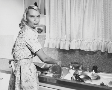 Portrait of a young woman washing pots and pans in a kitchen