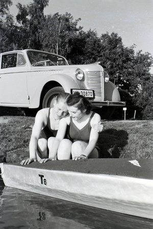 Young couple sitting in front of a boat at the river of a lake, Germany 1930s (b/w photo)