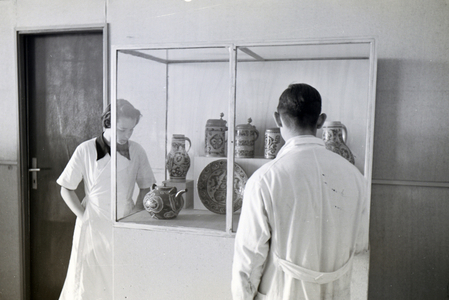Two students of the College for Ceramics in Höhr-Grenzhausen looking at the ceramics exhibited in the hallway of the school, Germany 1930s (b/w photo)