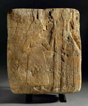 Relief with a male figure with feather-headgear, holding a staff …