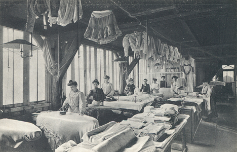 Interior view of a laundry with a line of women ironing (b/w photo)