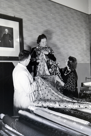 Employees of a textile factory in Krefeld are consulting and assisting a women with the purchase of fabric, Germany 1930s (b/w photo)