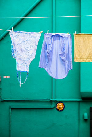 Linen drying on a line in front of a green-painted wall,

 Burano, 2023 (photo)