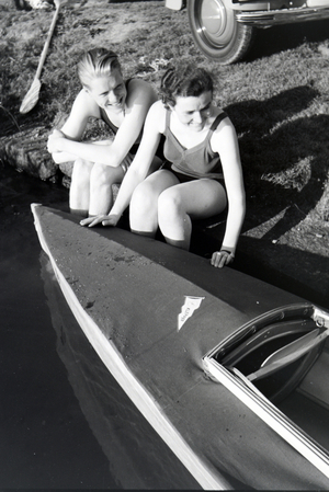 Young couple sitting in front of a boat at the river of a lake, Germany 1930s (b/w photo)