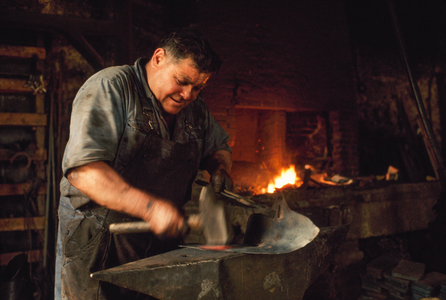 A blacksmith hammers metal on an anvil before a flaming forge. Chartres, France., 1960s (photo)
