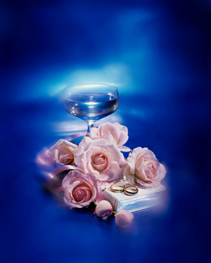 Roses with two wedding rings and the Bible near a wineglass