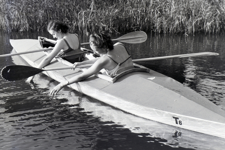 Two young women in bathing suits are paddling in a boat, Klepper T6 on a lake, Germany 1930s (b/w photo)