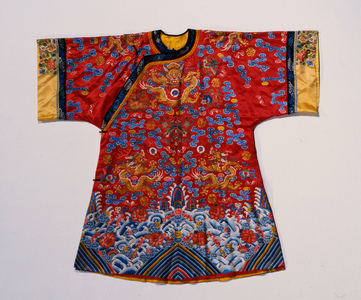 A semi formal robe of red satin embroidered in silks and gilt thread with dragons amidst scrolling clouds above a turbulent sea wave border (satin, silk)