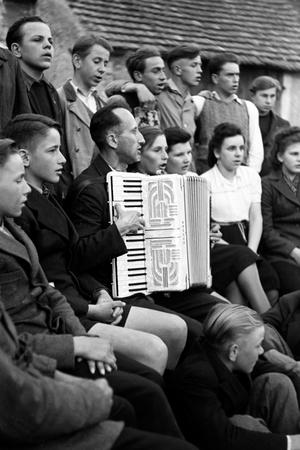 Priest Egon Voegler accompanying the yoith choir of Horka parish with his accordion, Germany 1949